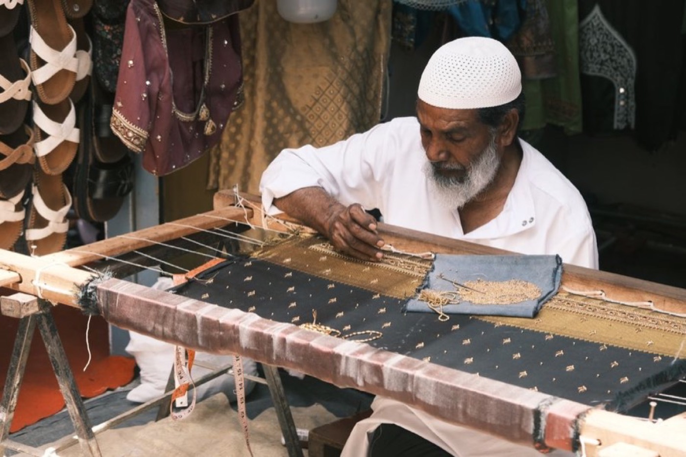 An artisan at a wooden trestle-mounted adda embroidery frame